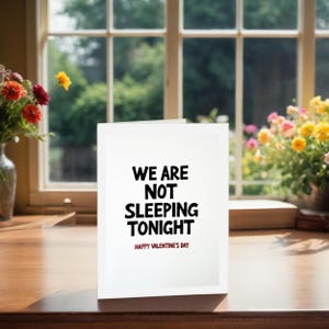Modern Valentine card displayed next to treats. The front shows simple bold text reading We are not sleeping tonight with a playful Valentine message.