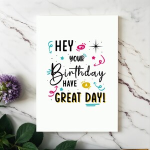 Showcased on a white granite countertop next to vibrant purple flowers, the Birthday Card adds a touch of charm and joy to any celebration.