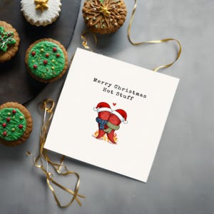 This card features 2 adorable hot peppers hugging in love, with a flame underneath and Santa hats for a holiday touch. The message Merry Christmas Hot Stuff adds a cute vibe, perfect for your partner this Christmas, showcased next to festive cookies