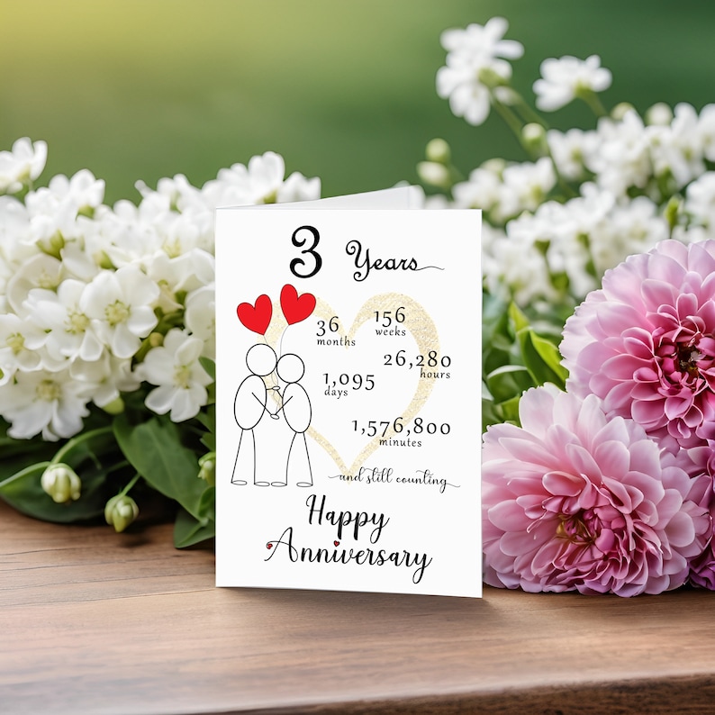 Celebrate your 3 year anniversary with an enchanting card featuring a gold heart, two intertwined heart balloons held by stick figures, and a backdrop of softly faded flowers for timeless elegance.
