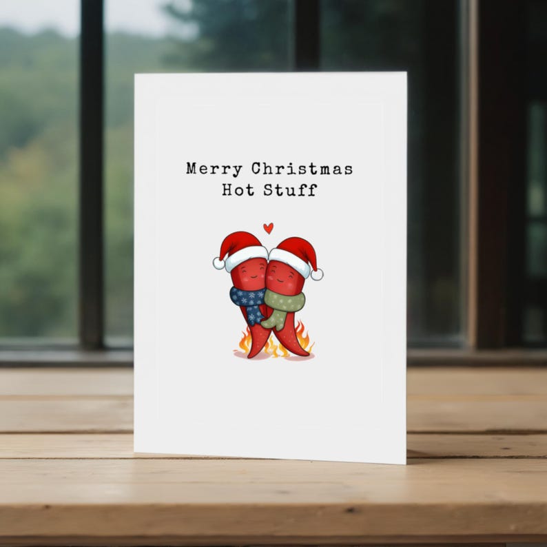 This card features 2 cute red hot peppers hugging in love, with a flame underneath and Santa hats for a holiday touch. The message Merry Christmas Hot Stuff adds a cuteness, perfect for your partner this Christmas, showcased in front of a window