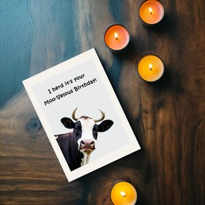 Set on a brown oak table with glowing candles, the Cow-themed Birthday Card brings a cozy and festive touch to the celebration.