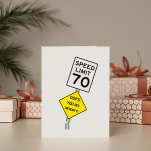 Celebrate their 70th birthday with a quirky 'Oops You Hit 70' Birthday Card, showcased next to birthday presents. This charming card adds a special touch, enhancing their celebration and making their milestone birthday even more memorable.