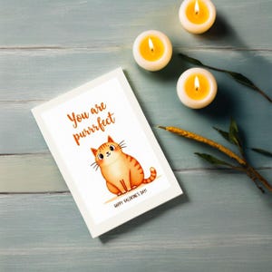 Sweet Valentine greeting card displayed next to candles. The design highlights a smiling orange cat with the playful text You are purrrfect.