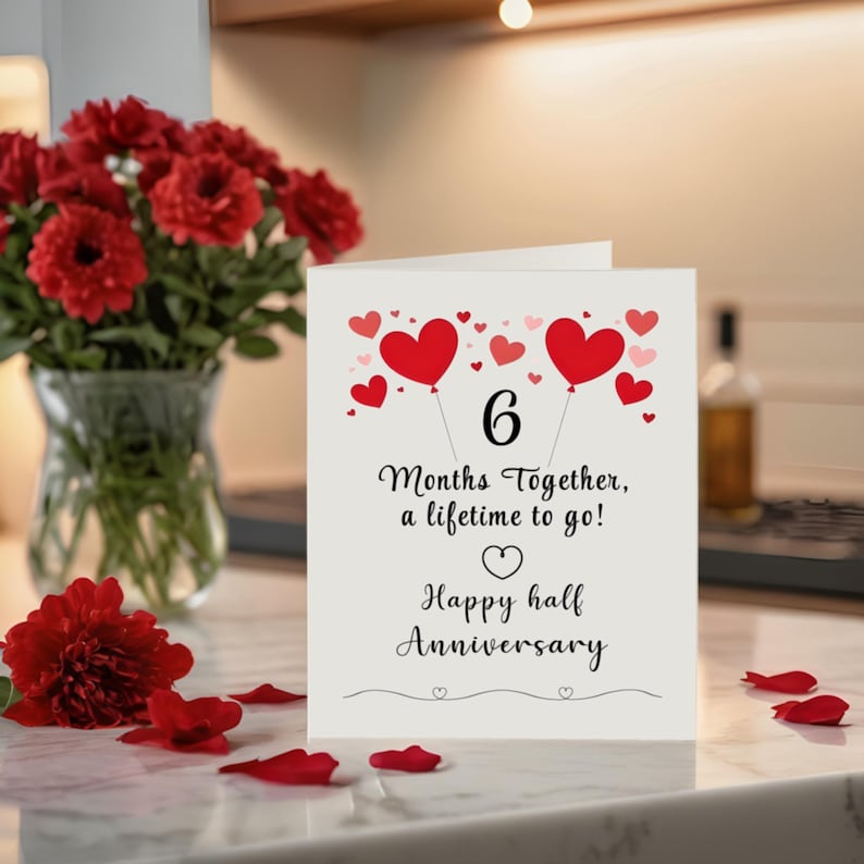 Celebrate your 6 month anniversary with a card featuring tiny red and pink hearts, a heartfelt message '6 months together, a lifetime to go!' near red flowers in a vase. This elegant design beautifully captures the joy of your 6 month milestone.
