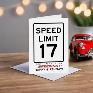 Celebrate their 17th birthday with a charming Speed Limit Birthday Card, beautifully displayed alongside a classic red model car. This delightful pairing adds a nostalgic touch to their special birthday.