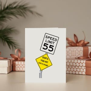Celebrate their 55th birthday with a quirky 'Oops You Hit 55' Birthday Card, showcased next to birthday presents. This charming card adds a special touch, enhancing their celebration and making their milestone birthday even more memorable.