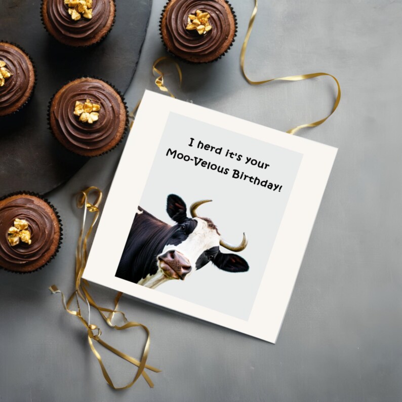 Displayed on a table next to delicious chocolate cupcakes, the 'Moo-velous Birthday' Card adds a sweet and cheerful touch to the party.