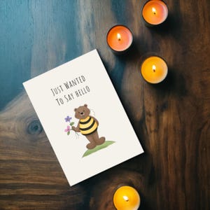 Set on a brown oak table with glowing candles, the 'Just Wanted To Say Hello' Card brings a cozy and thoughtful touch to any occasion