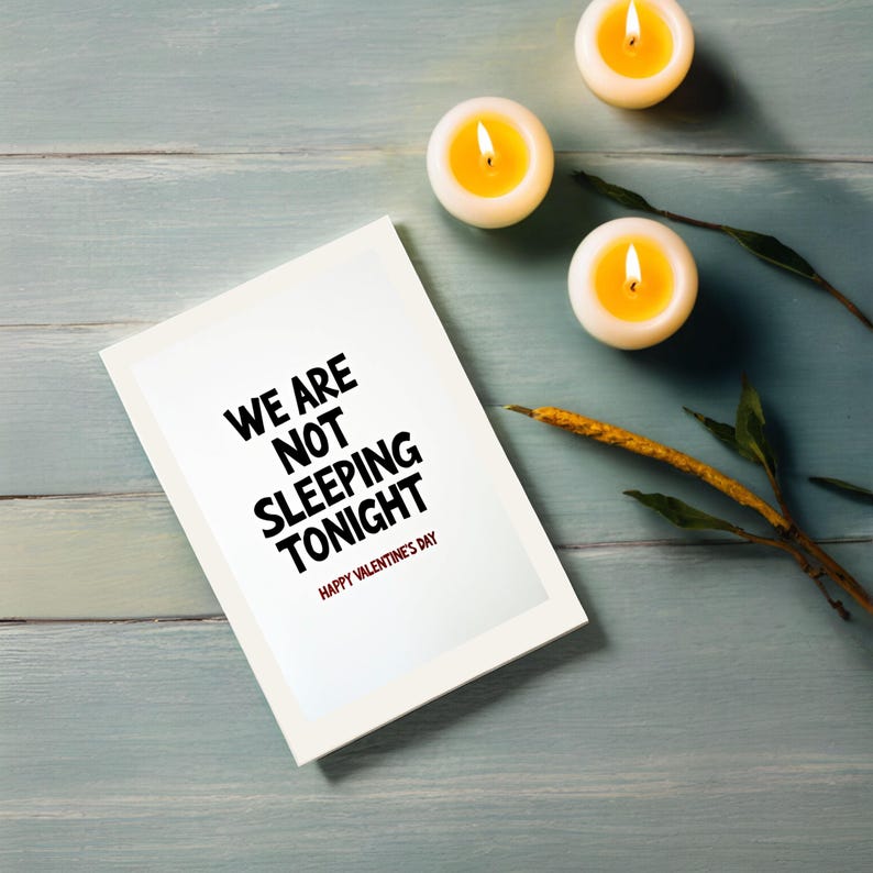 Humorous Valentine greeting card displayed next to candles. The design focuses on bold typography with the phrase We are not sleeping tonight.