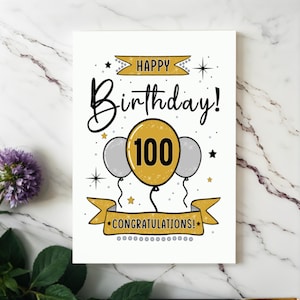 Celebrate their 100th birthday with our elegant Happy 100th Birthday card, beautifully presented next to purple flowers on a white granite countertop.