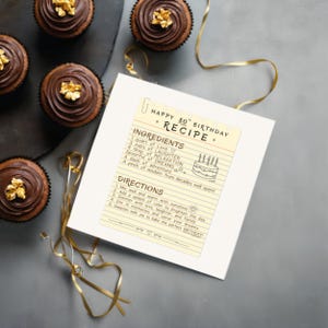 Wish someone a 80th birthday with a one of a kind recipe birthday card, displayed next to chocolate cupcakes. This birthday card features ingredients like relaxation, dreams, and laughter. It's a creative way to wish them a happy 80th birthday.