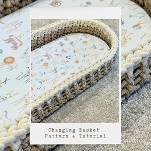 May include: A beige and white crocheted changing basket with a white fabric liner featuring a pattern of animals and letters. The text "Changing Basket Pattern & Tutorial" is printed on the image.
