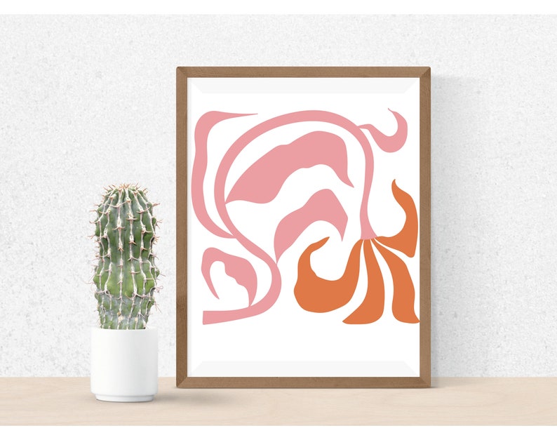 May include: Abstract art print with a pink and orange floral design in a brown frame. The print is on white paper.