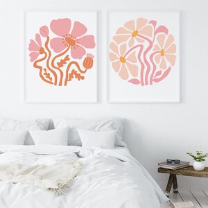 May include: Two framed prints with pink and orange floral designs. The prints feature stylized flowers with rounded petals and stems.