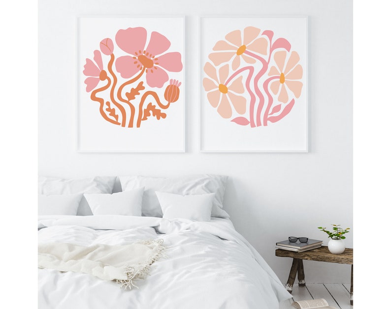 May include: Two framed prints with pink and orange floral designs. The prints feature stylized flowers with rounded petals and stems.