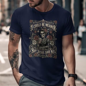 T-shirt with skeleton, roses, and text "I COULD BE MEANER BUT JESUS SAID NO".