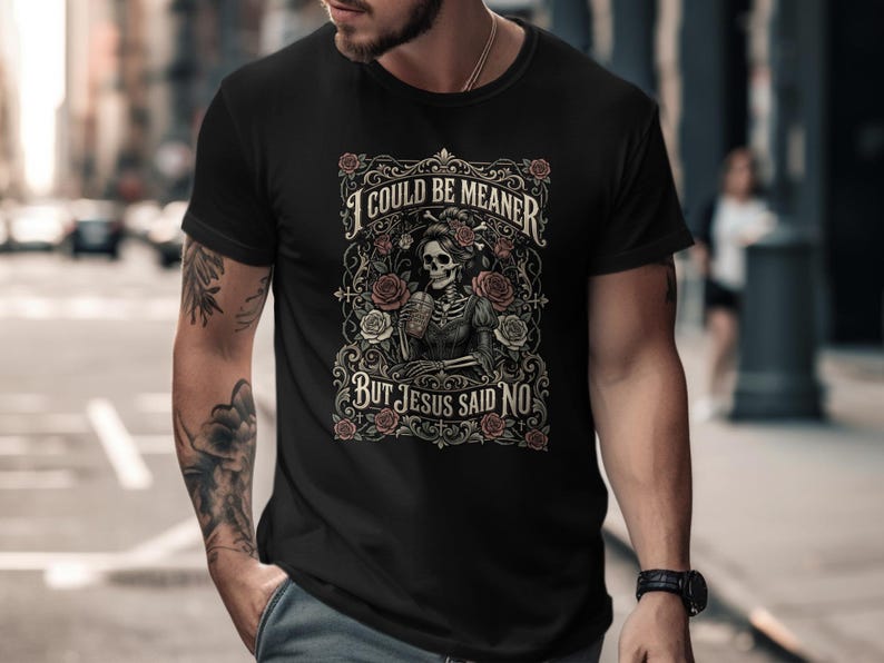 Black t-shirt with skeleton and roses graphic, "I COULD BE MEANER BUT JESUS SAID NO".
