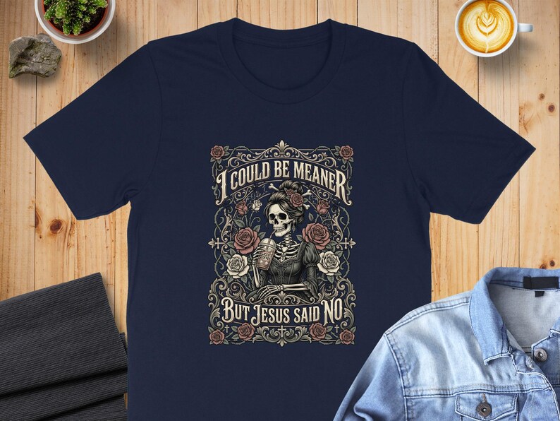Dark t-shirt with skeleton, roses, and text "I COULD BE MEANER BUT JESUS SAID NO".