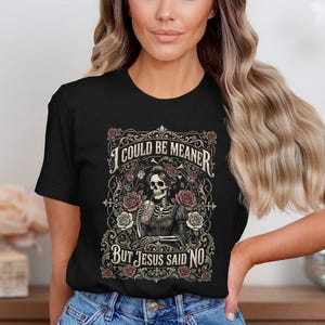Black t-shirt with skeleton, roses, and text "I COULD BE MEANER BUT JESUS SAID NO".