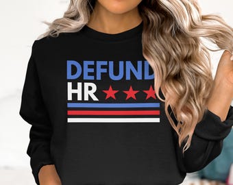 May include: Black sweatshirt with the words "DEFUND HR" in blue and white, with three red stars. Below the text are three horizontal stripes in red, blue, and white. The sweatshirt is a casual style.