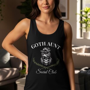 May include: Black tank top with the text "GOTH AUNT Social Club" in white script. The design features a skull wearing sunglasses and a bandana, surrounded by a green wreath. A casual, gothic-themed apparel item.
