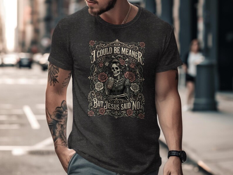 Dark t-shirt with skeleton, roses, and text "I COULD BE MEANER BUT JESUS SAID NO".