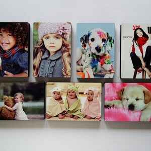 May include: A collage of nine photos featuring children, animals, and a woman. The photos are printed on square tiles and arranged in a grid pattern. The photos include a young girl with a teddy bear, a girl with a colorful dalmatian, a girl with a pink hat, a girl with a red headband, and three babies.