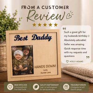 May include: A wooden picture frame with the words "Best Daddy" in navy blue script. The frame holds a photo of a man and child. The text "HANDS DOWN!" and "Love, Hunter Lane" are also visible. The frame is a keepsake.