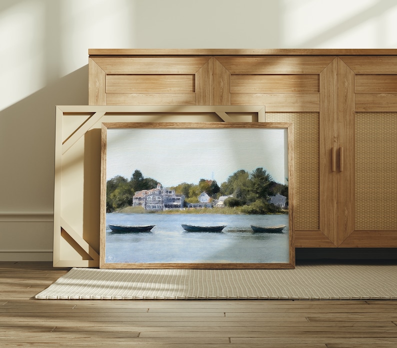 May include: A framed painting of a waterfront scene with a small town in the background. The painting features four boats on the water and a blue sky with white clouds.