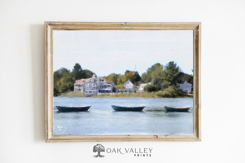 May include: A framed watercolor painting of a lake scene with three small boats in the foreground and a large house on the far shore. The house is painted in shades of gray and white, and the lake is a light blue color. The sky is a pale blue with some clouds.
