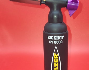 May include: A black torch lighter with a purple nozzle and a hexagonal purple base. The torch is labeled "BIG SHOT GT 8000" and has the word "BLAZER" in yellow lettering.