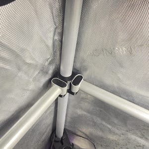 Puede incluir: Una estructura de marco de metal plateado con conectores de esquina de plástico negro dentro de una tienda de cultivo plateada reflectante. Las paredes tienen un patrón de diamante y el texto AC INFINITY está grabado en el panel.