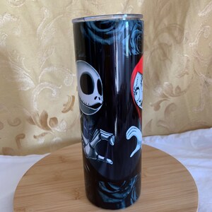 Puede incluir: Un vaso negro con Jack Skellington y Sally de The Nightmare Before Christmas. El dise&ntilde;o incluye rosas negras y un fondo oscuro. El vaso es cil&iacute;ndrico y parece ser de acero inoxidable.