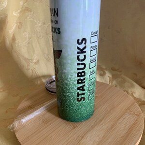 以下が含まれることがあります： グリーングリッターのデザインとスターバックスのロゴが入った白いスターバックスタンブラー。タンブラーには蓋とストローが付いています。タンブラーのテキストは「...man I live on Starbucks...」と飲み物の注文フォームです。