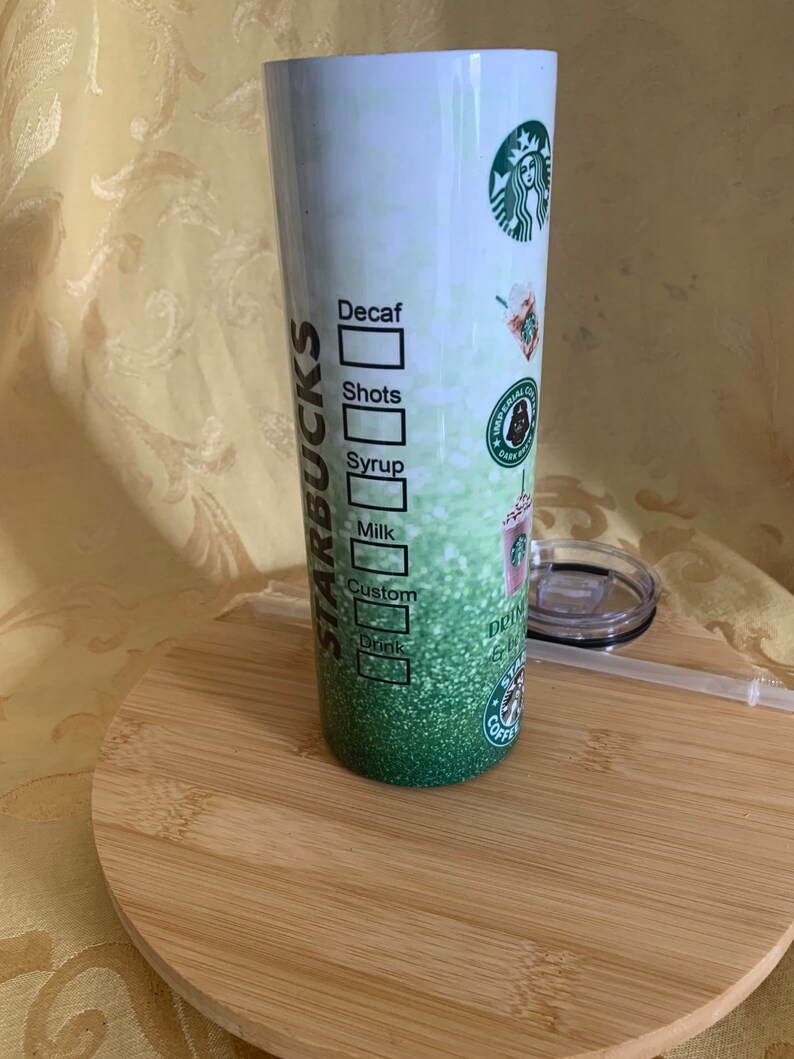 以下が含まれることがあります： スターバックスのデザインが施された、背の高い断熱タンブラー。タンブラーは、スターバックスのロゴとドリンクのカスタマイズオプションを備えた、グラデーションの緑色の背景が特徴です。蓋とストローが含まれています。