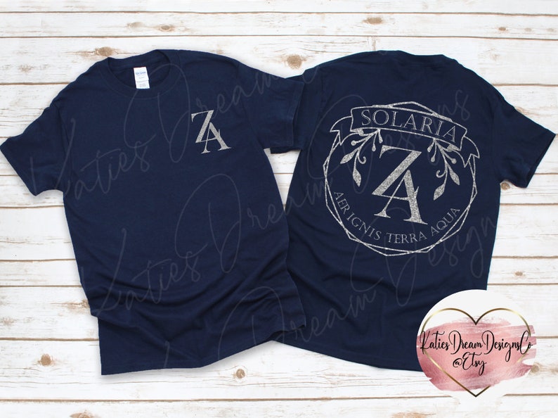 May include: Navy blue t-shirts with a silver glitter design. One shirt has a large "ZA" on the front. The other shirt has a "ZA" inside a circular design with the word "SOLARIA" and the text "AER IGNIS TERRA AQUA".
