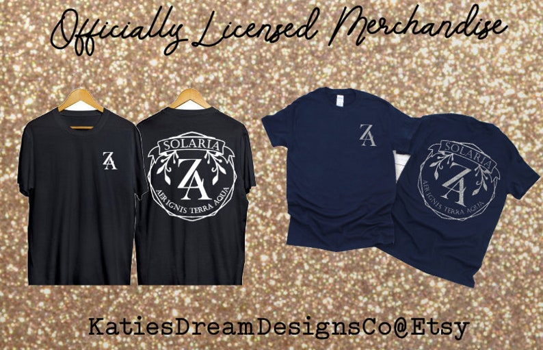 May include: Black and navy blue t-shirts with white graphic designs. The shirts display the letter "A" and the text "SOLARIA AER IGNIS TERRA AQUA". The image also includes the text "Officially Licensed Merchandise" and "KatiesDreamDesignsCo@Etsy".