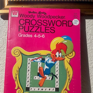 May include: A pink and green book cover featuring a cartoon image of Woody Woodpecker. The book title is "Walter Lantz Woody Woodpecker Crossword Puzzles" and the subtitle is "Grades 4-5-6".