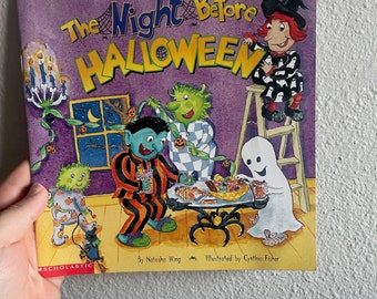 May include: A purple book cover with the title "The Night Before HALLOWEEN" in yellow and black lettering. The cover features illustrations of a witch, a ghost, a monster, and a creature with a pumpkin on its head. The book is published by Scholastic.