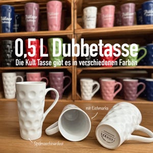 Könnte beinhalten: Eine weiße Keramiktasse mit einer Noppen-Oberfläche und einem Henkel. Die Tasse hat ein Fassungsvermögen von 0,5 Litern und ist spülmaschinenfest. Der Text "0,5L Dubbetasse" und "Die Kult Tasse gibt es in verschiedenen Farben" ist auf dem Bild zu sehen.
