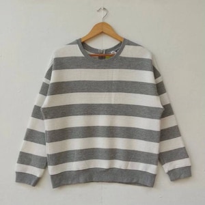 May include: Grey and white striped long-sleeved sweater with a round neckline.