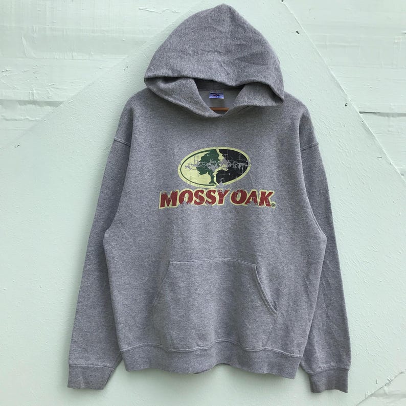 May include: Gray hooded sweatshirt with a Mossy Oak logo featuring a tree in a camouflage pattern. The logo is in red, green, and yellow.