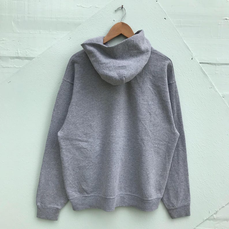 May include: A gray hooded sweatshirt with a drawstring hood. The sweatshirt has long sleeves and a kangaroo pocket.