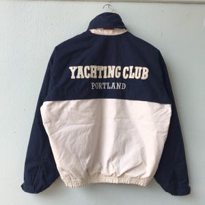 May include: A navy blue and white windbreaker jacket with the text "Yachting Club Portland" on the front.
