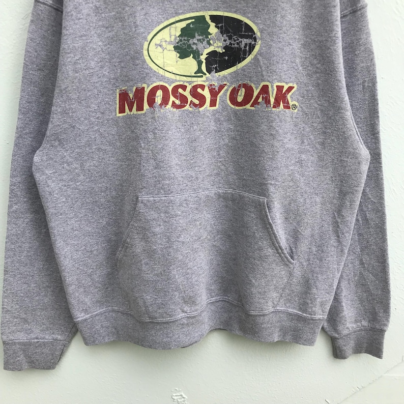 May include: Gray hooded sweatshirt with a Mossy Oak logo featuring a green tree and the words "Mossy Oak" in red.