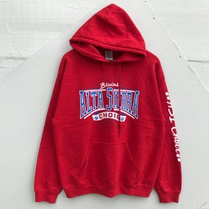 May include: A red hooded sweatshirt with the text "Bruins ALTA SIERRA CHOIR" in blue and white lettering across the chest. The sleeve has white text. The sweatshirt has a front pocket and a drawstring hood.