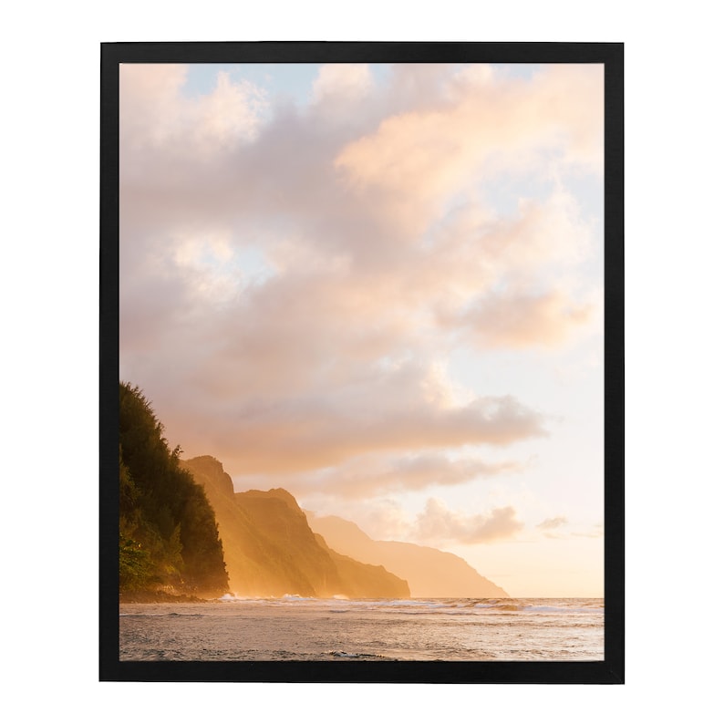 May include: A scenic photograph of a coastline with a lush green mountain range in the foreground. The sky is a vibrant orange and pink, with fluffy white clouds. The ocean is a deep blue, with waves crashing on the shore.