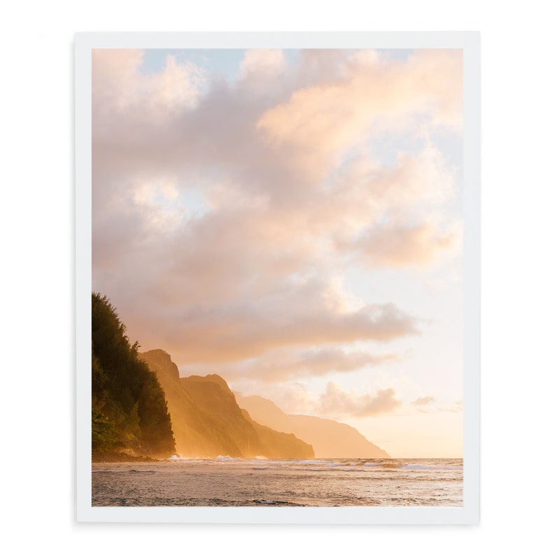 May include: A scenic photograph of a coastline with lush green cliffs and a bright blue sky with fluffy white clouds. The sun is setting, casting a warm golden glow over the scene.
