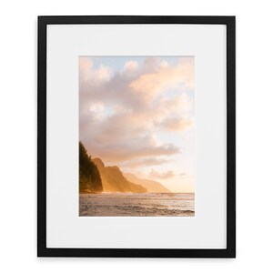 May include: A photograph of a beach scene with a rocky coastline and a cloudy sky. The sky is a mix of blue, pink, and orange, and the clouds are fluffy and white. The water is a deep blue, and the waves are crashing on the shore. The rocks are a dark brown, and the trees are a lush green.